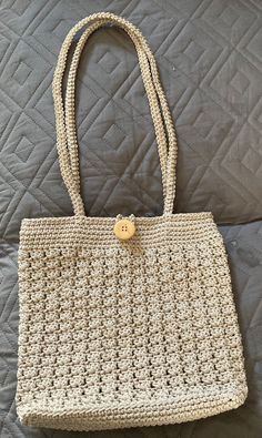 a crocheted purse sitting on top of a quilted bed with a button in the middle