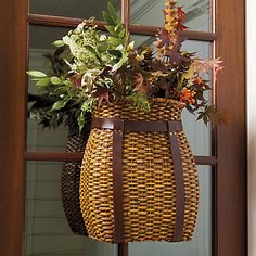 a basket hanging from the side of a door with plants in it and another plant inside