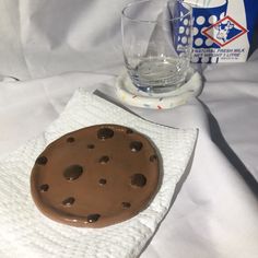 a chocolate cookie sitting on top of a white napkin next to a glass of water