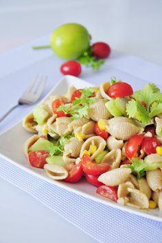 a white plate topped with pasta salad next to a fork