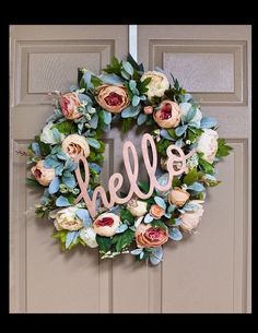 a wreath with the word hello written on it and some flowers hanging from the front door