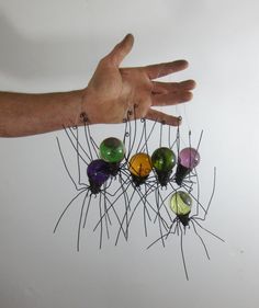 a hand is holding several pins in the shape of an object with multiple colors on them