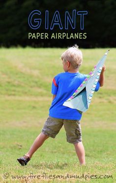 a young boy holding a paper airplane in the grass with text overlay that reads giant paper airplanes