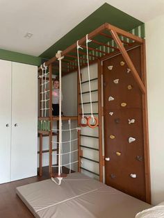 a child standing on top of a bed in a room with climbing ropes attached to the wall