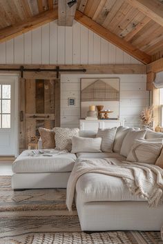 a living room filled with lots of furniture and wooden beams on the ceiling, along with a large white sectional couch