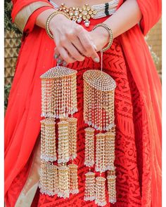 a woman in an orange dress holding some gold jewelry