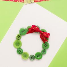 a bracelet made out of buttons and a red ribbon on top of a white card