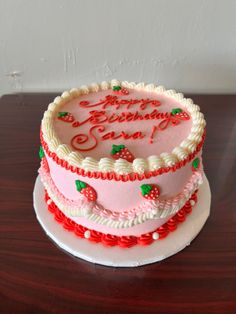 a pink and white cake sitting on top of a wooden table