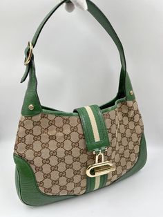 A stunning vintage Gucci Jackie bag made from the iconic GG beige canvas with green leather trim and pale gold hardware. This bag also has a bold G closure on the front of the bag. Inside the bag is lined with brown cotton lining and there is a zipped pocket for valuables. This bag is in good vintage condition with some slight wear to the base edges and leather parts. There is a mark on the back of the green and cream webbing strap. A true collectors item and comes with the original Gucci dust b Vintage Gucci Jackie, Vintage Gucci Bag, Jeans For Girls, Shoes For Summer, Bags Ideas, Gucci Vintage, Bag Inside, Sorority Outfits, Church Hats