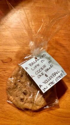 a cookie wrapped in plastic sitting on top of a wooden table next to a sign