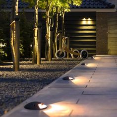 a bike is parked in front of a house at night with lights on the driveway