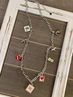 a necklace with charms hanging from it's sides on a window sill in front of a wall