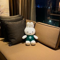 a stuffed rabbit sitting on top of a couch next to pillows and a pillow case