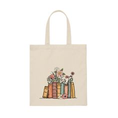 a tote bag with books and flowers on it, sitting in front of a white background