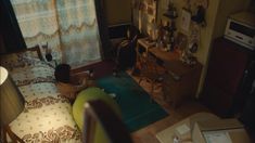 a young boy sitting on top of a bed next to a desk and chair in a bedroom