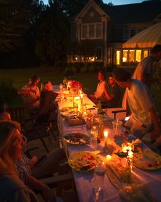 a group of people sitting around a table with food and candles in front of them