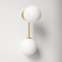 two white balls mounted on a gold plated metal wall light with one ball in the middle