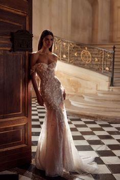 a woman in a wedding dress leaning against a door with her hand on the side