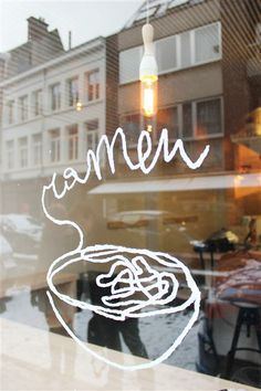 a window with the words women written on it and a bowl of noodles in front