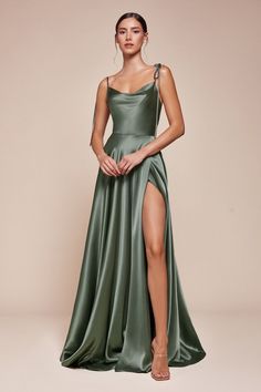 A woman stands confidently in a flowing green satin dress with a high slit, showcasing her leg. The backdrop is a soft beige, enhancing the elegance of the outfit. Bridesmaid Dress Styles Satin, Silky Dress Long, Cinderella Divine, Shirt Jacket Men, Drape Maxi Dress, Selling Design, Designer Drapes, Long Sleeve Blazers, Satin Gown