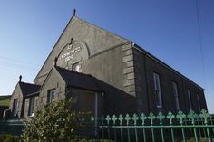 an old building with a green fence around it