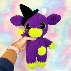 a hand holding a purple and yellow stuffed animal