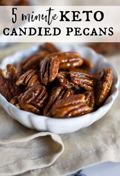 a white bowl filled with candied pecans sitting on top of a cloth covered table