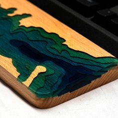 a wooden mouse pad sitting on top of a computer keyboard, with an image of a lake in the background