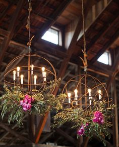 two chandeliers hanging from the ceiling with flowers and greenery on each one