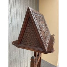 an old wooden clock with intricate carvings on it's face and sides, in front of a corrugated wall