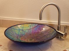 a glass bowl sink sitting on top of a bathroom counter next to a faucet