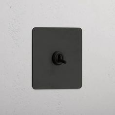 a black square light switch on a white wall