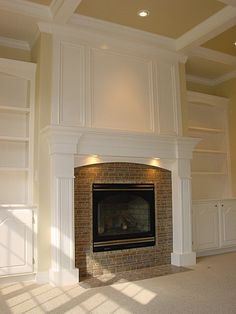 an empty living room with a fireplace and built in shelves