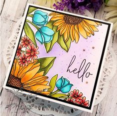 a card with sunflowers and the word hello on it, sitting next to some flowers