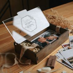 an open wooden box filled with photos on top of a table next to other items