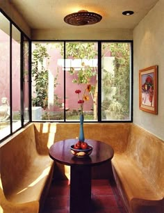 a wooden table sitting under a window next to a bench