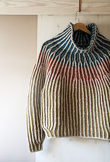 a sweater hanging up on a wall with a wooden hanger in front of it