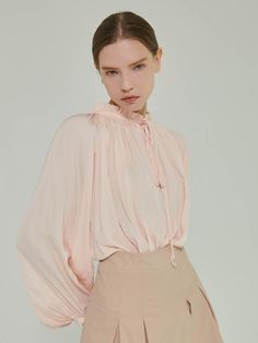 Charming blouse featuring the subtle glossy surface, and shirring detail. The natural draped silhouette and voluminous sleeves create feminine mood. The half-neck design with ribbon string is also accentuated. Style with various bottoms like skirts, denim jeans, or trousers to create feminine looks. - Half-neck and with ruffle trim and ribbon string detail- Delicate shirring detail at front- Pearl button closure detail at sleeve hems- Slim and relaxed silhouette- Viscose blended fabric that has glossy surface Feminine Spring Blouse With Gathered Neckline, Chic Blouse With Gathered Neckline For Spring, Elegant Ruffled Tops For Gatherings, Elegant Long Sleeve Blouse For Gatherings, Chic Puff Sleeve Blouse For Gatherings, Elegant Pink Blouse With Balloon Sleeves, Chic Blouse For Gatherings, Elegant Summer Blouse For Gatherings, Feminine Ruched Blouse