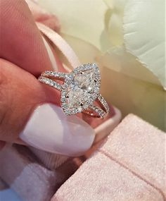 a woman's hand holding an engagement ring with two diamonds on the top and bottom