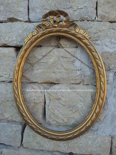 an ornate gold frame hanging on a stone wall with a knot around the edge and two rings at the top