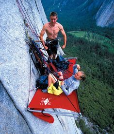 two men hanging out on the side of a mountain while another man stands next to them