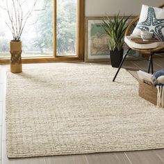 a living room area with a rug, chair and potted plant