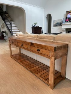 a wooden table sitting in the middle of a living room next to a white couch