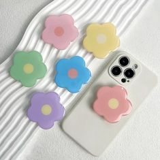 four flower shaped cell phone cases sitting on top of a white table next to each other