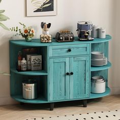 a blue cabinet with plates and cups on it next to a potted plant in the corner