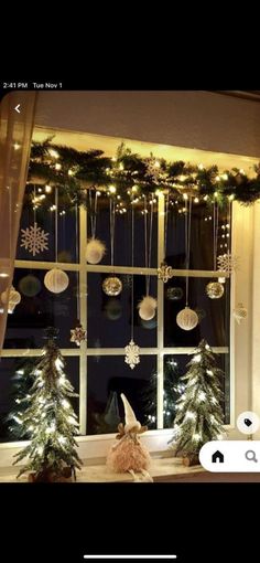 a window with christmas decorations hanging from it's side and lights on the windowsill