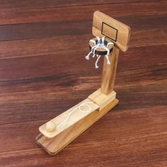 a wooden toy basketball hoop with a spider on it's back and net in the middle