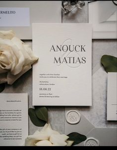 the wedding stationery is laid out with white flowers