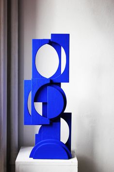 a blue sculpture sitting on top of a white table next to a wall and window