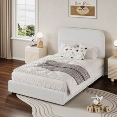 a white bed sitting on top of a wooden floor next to two nightstands and a window